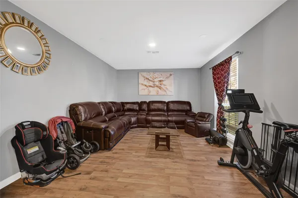 a living room with furniture a flat screen tv and gym equipment
