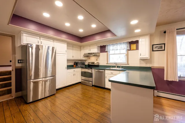 a kitchen with granite countertop a refrigerator stove and wooden floor