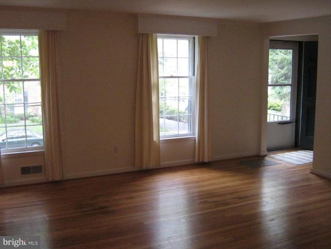 7103 Wardman Road Baltimore, MD 21212 - Photo 4 of 19 a view of an empty room with wooden floor and a window