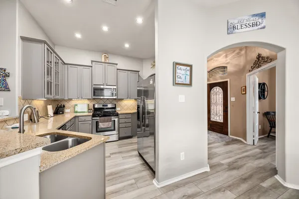 a kitchen with stainless steel appliances granite countertop a sink a refrigerator and cabinets