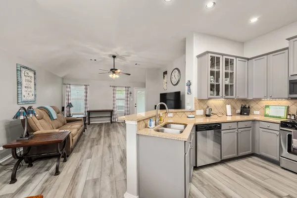 a open kitchen with cabinets a sink and a stove with wooden floor