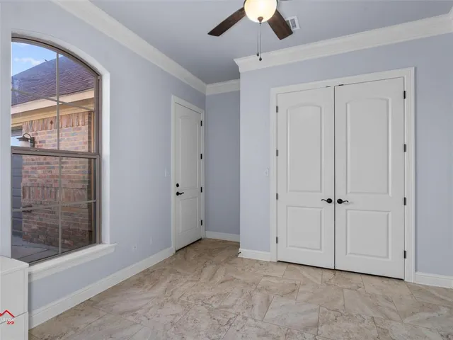 an empty room with windows and fan