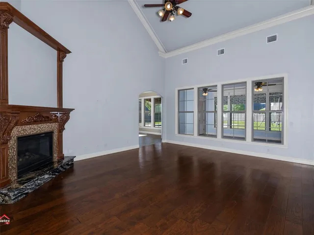 a view of an empty room with wooden floor and a fireplace