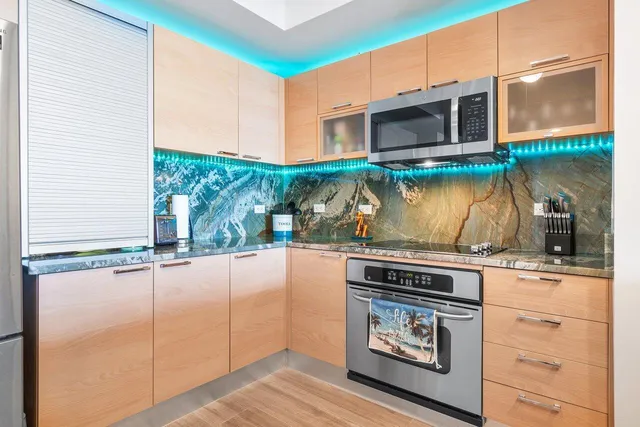 a kitchen with stainless steel appliances granite countertop a sink a stove and a wooden floors