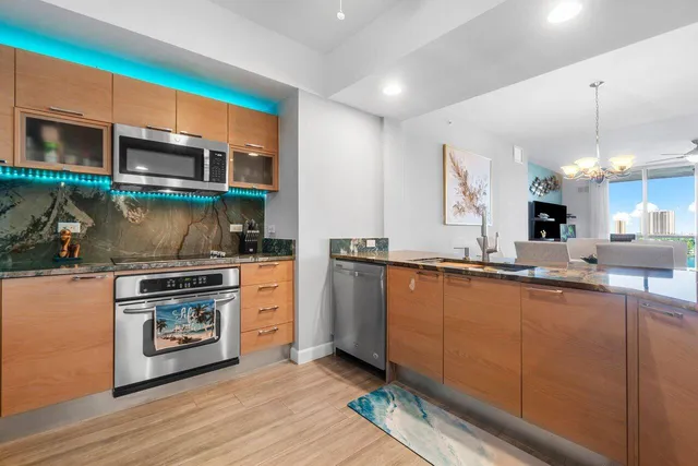 a open kitchen with stainless steel appliances kitchen island granite countertop a sink and a refrigerator