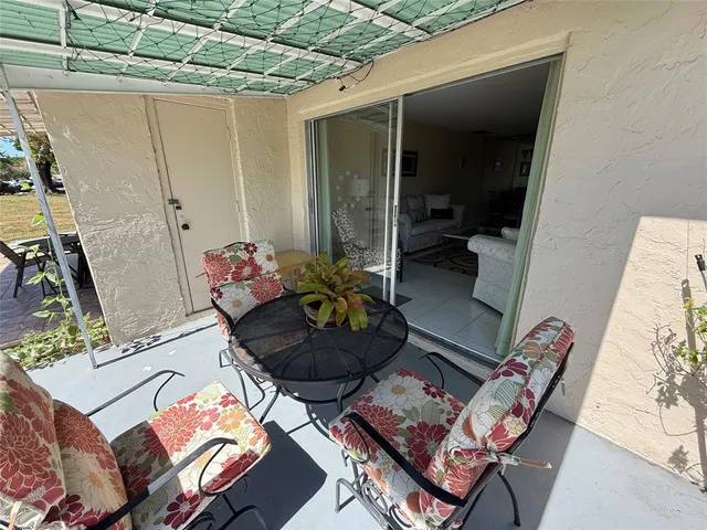 a view of a chairs and table in the patio next to a yard