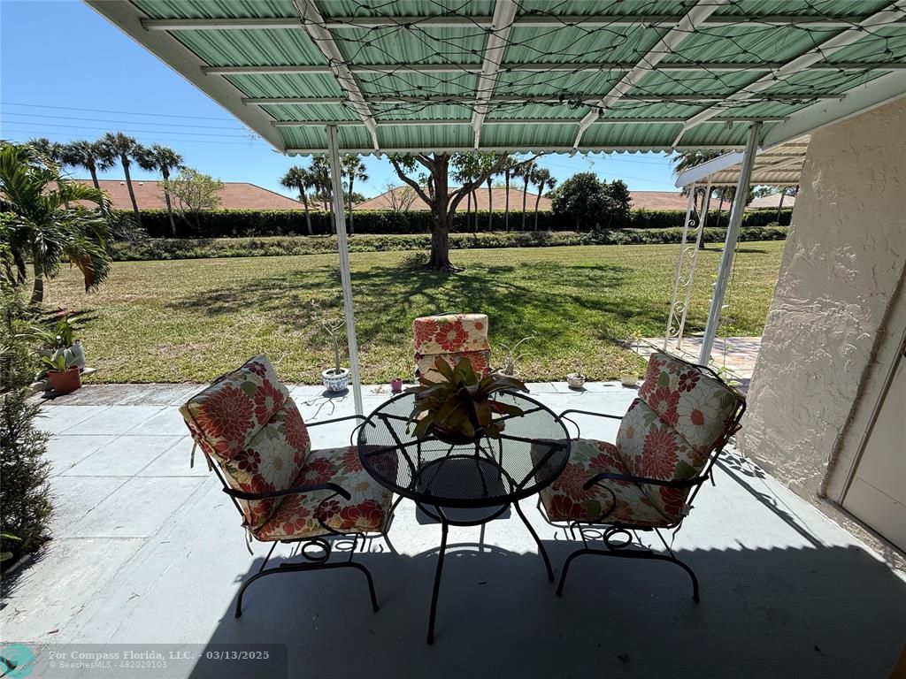 8540 Chevy Chase Drive, Unit 183 Boca Raton, FL 33433 - Photo 14 of 21 a view of a chairs and table in the patio next to a yard