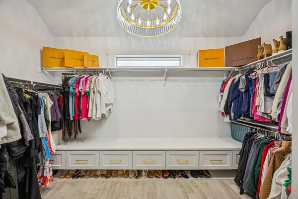 a view of walk in closet with clothes and shoes