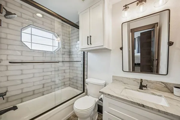 a bathroom with a granite countertop toilet a sink and mirror