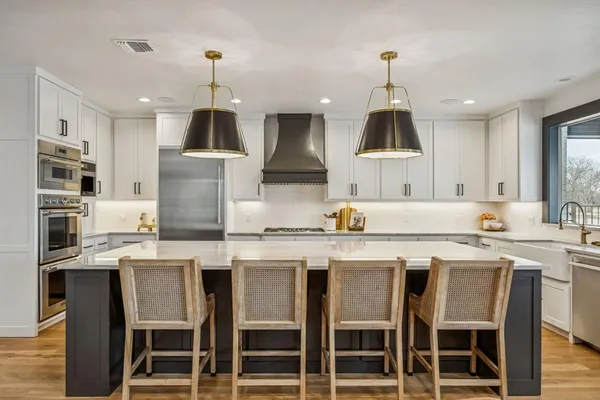 a kitchen with stainless steel appliances granite countertop a dining table chairs sink and cabinets