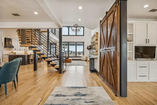 a living room with stainless steel appliances furniture wooden floor and a view of kitchen
