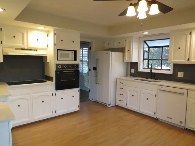 a kitchen with granite countertop white cabinets white stainless steel appliances and wooden floors