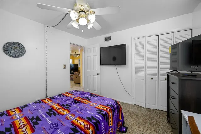 a bedroom with a bed a flat screen tv and chandelier
