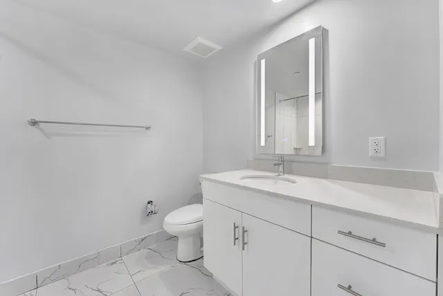 a bathroom with a granite countertop sink a toilet and a mirror