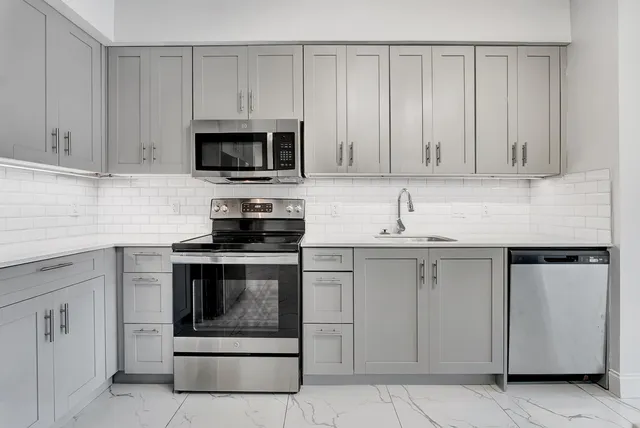 a kitchen with white cabinets and stainless steel appliances