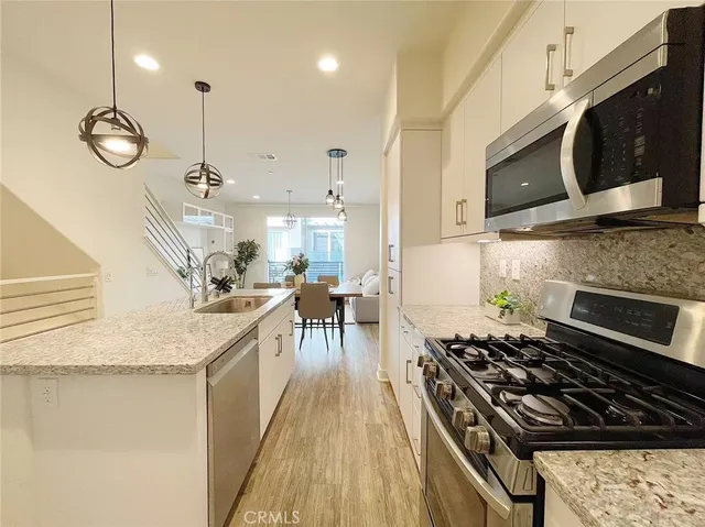 a kitchen with stainless steel appliances granite countertop a stove a sink and a microwave