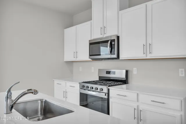 a kitchen with granite countertop a sink a stove and cabinets