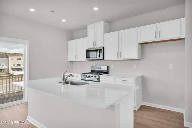 a kitchen with white cabinets and wooden floor