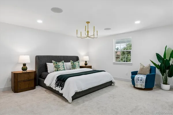 a spacious bedroom with a bed a couch and a potted plant