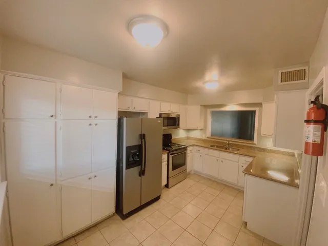 a kitchen with granite countertop a refrigerator and a stove top oven