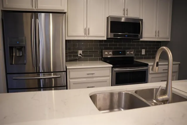 a kitchen with granite countertop a refrigerator and microwave