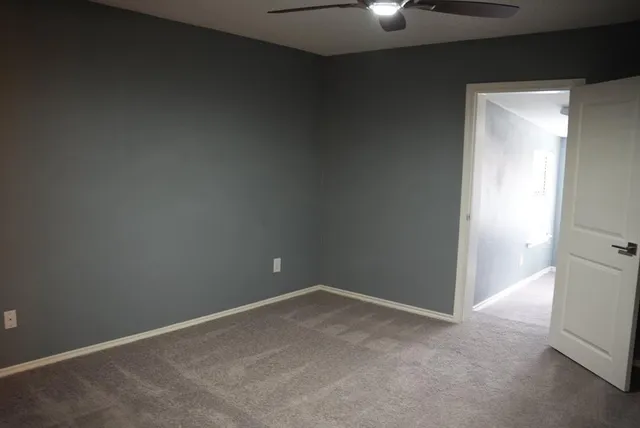 a view of an empty room and chandelier fan