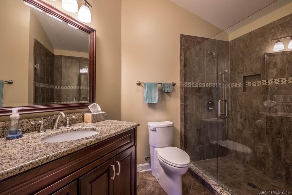 1115 Torrence Circle, Unit 63 Davidson, NC 28036 - Photo 13 of 23 a bathroom with a granite countertop toilet sink and shower