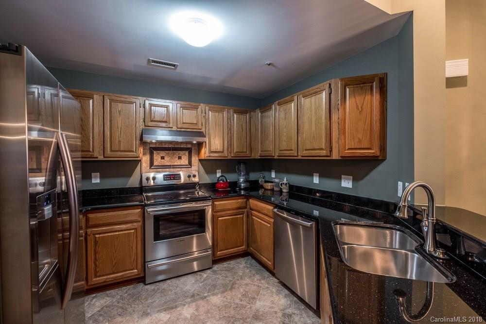 1115 Torrence Circle, Unit 63 Davidson, NC 28036 - Photo 3 of 23 a kitchen with kitchen island granite countertop a sink stainless steel appliances and cabinets