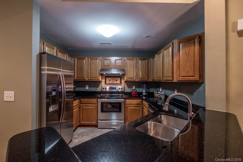 1115 Torrence Circle, Unit 63 Davidson, NC 28036 - Photo 4 of 23 a kitchen with kitchen island granite countertop a sink stainless steel appliances and cabinets