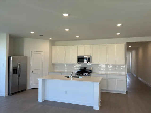 a kitchen with stainless steel appliances white cabinets a refrigerator and a stove