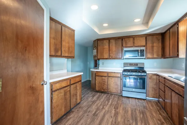 a kitchen with stainless steel appliances granite countertop a stove a sink and a refrigerator with wooden cabinets