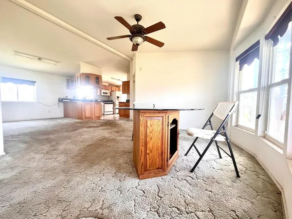 an empty room with chandelier fan and windows