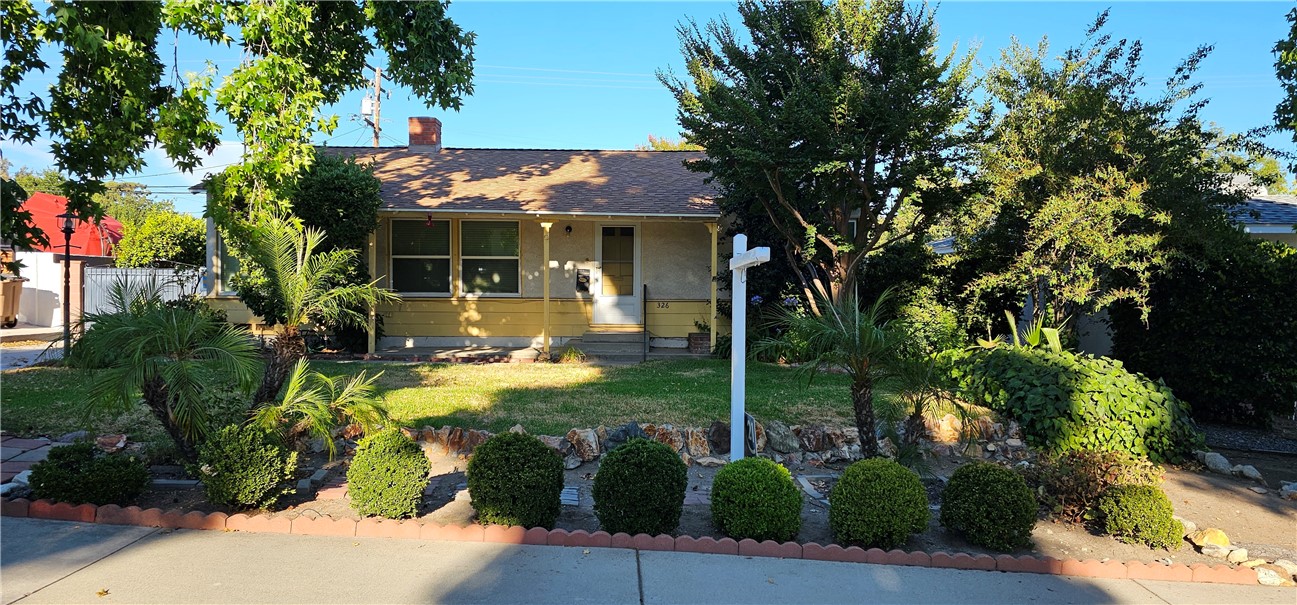 a view of a white house with a big yard and potted plants