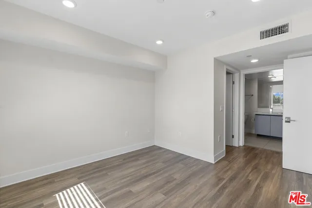 a view of a hallway with wooden floor and a kitchen