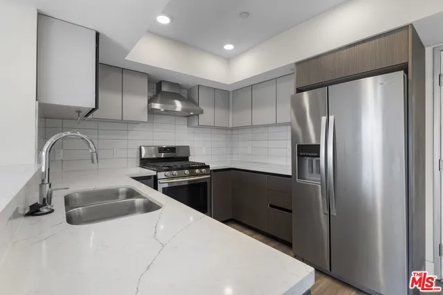 a kitchen with stainless steel appliances granite countertop a refrigerator a sink a stove and a refrigerator