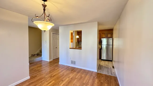 a view of an empty room with wooden floor and a ceiling fan