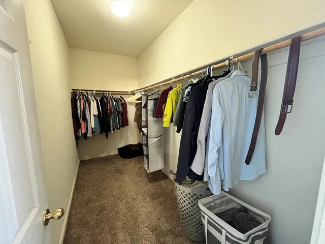a view of walk in closet with clothes and shoes