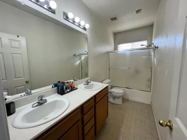 a bathroom with a double vanity sink mirror and toilet