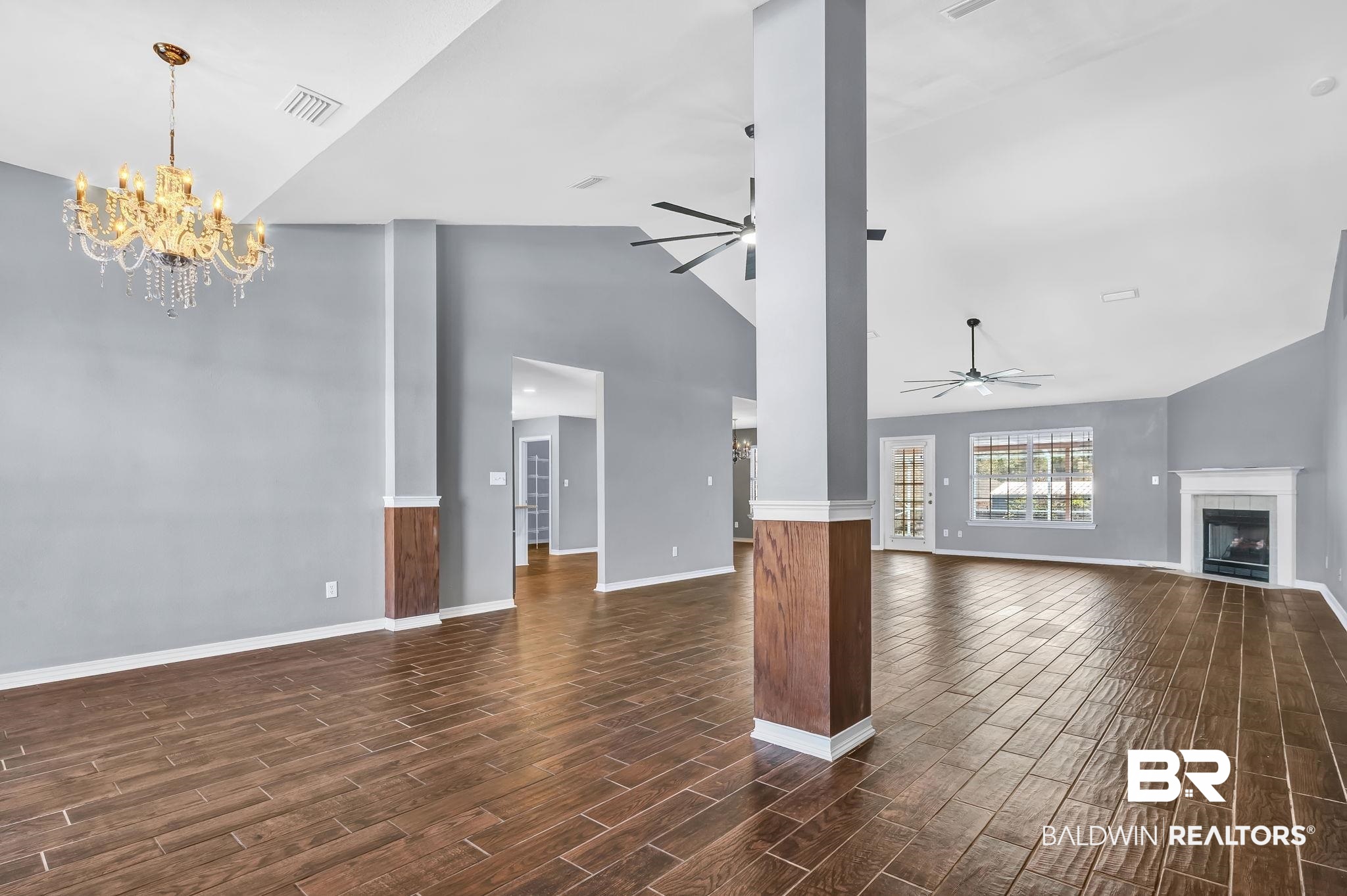 16444 Hamlet Lane Foley, AL 36535 - Photo 11 of 49 Unfurnished living room with ceiling fan with notable chandelier, baseboards, dark wood-style floors, visible vents, and a fireplace