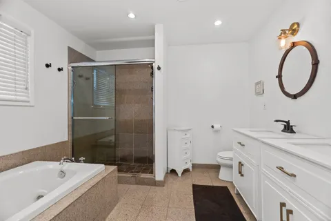 a spacious bathroom with a tub sink and mirror