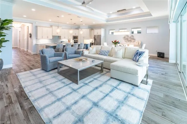 a living room with couches and kitchen view with wooden floor