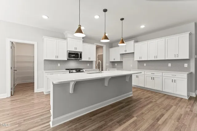 a kitchen with stainless steel appliances granite countertop a sink a stove a microwave a center island and cabinets