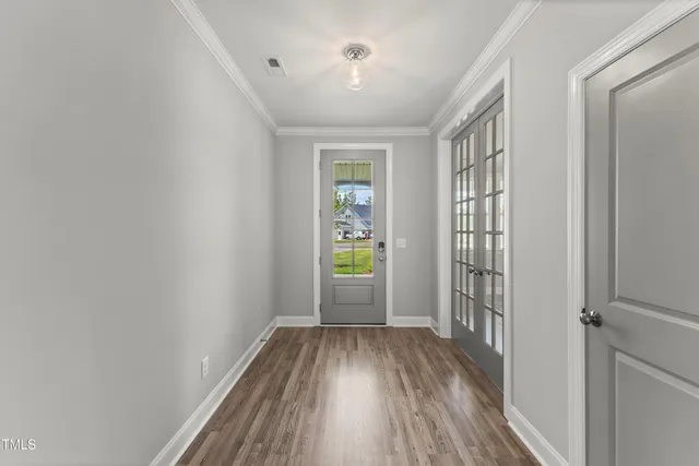 a view of an empty room with wooden floor fireplace and a window