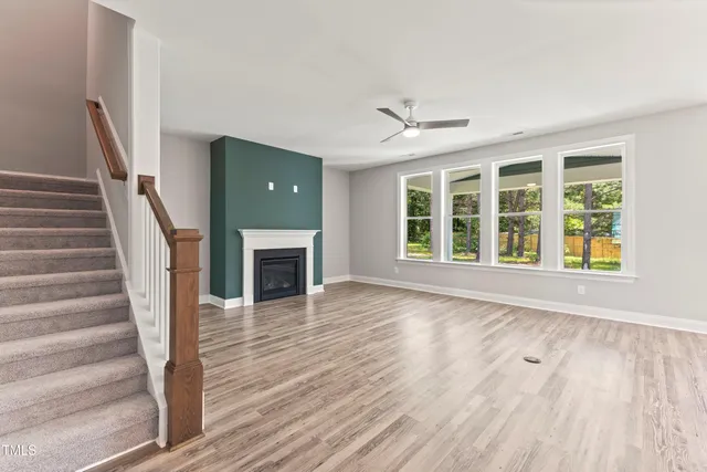 a view of an empty room with wooden floor fireplace and a window