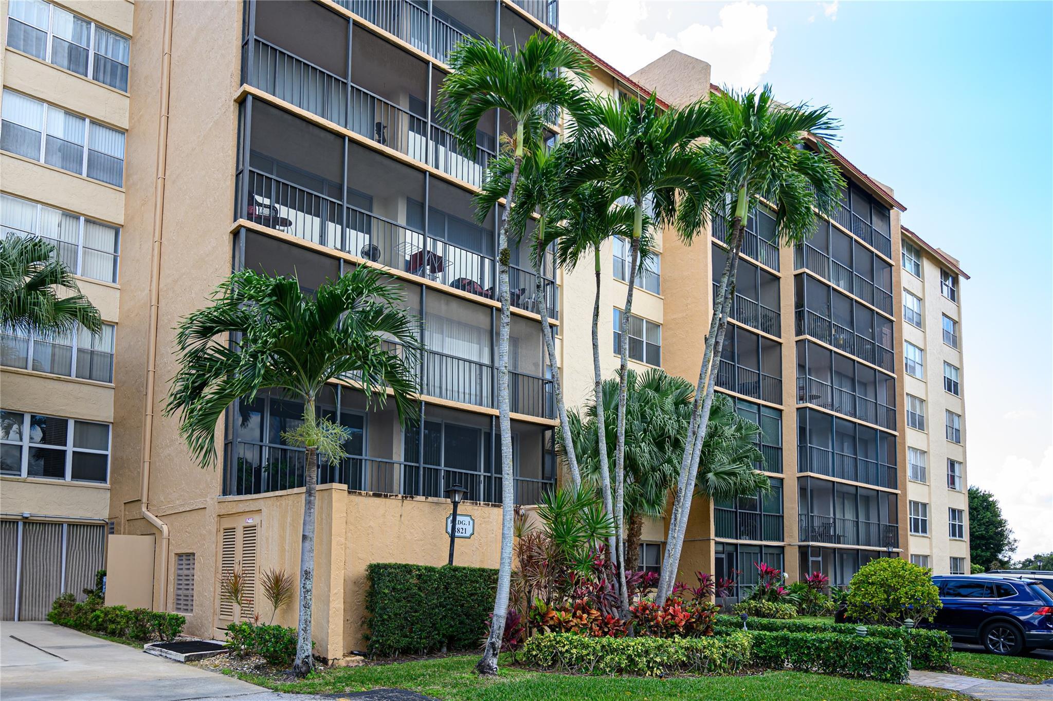 a front view of multi story residential apartment building with yard and green space