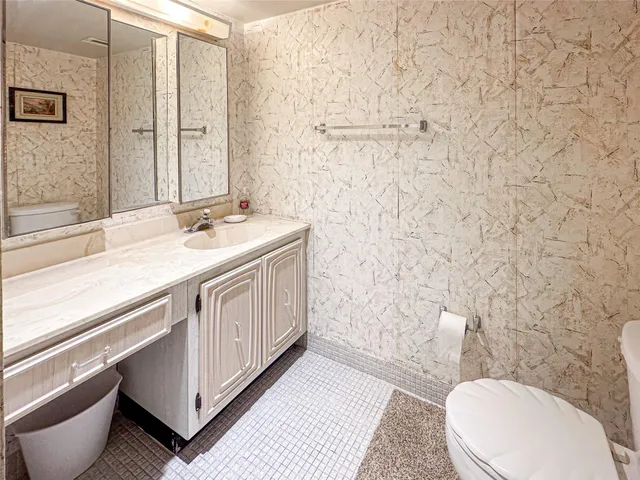 a bathroom with a granite countertop toilet sink and mirror