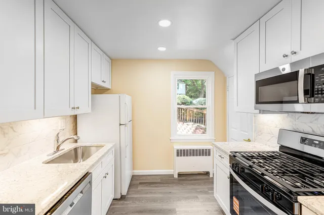 a kitchen with stainless steel appliances a sink a stove a microwave a sink and cabinets