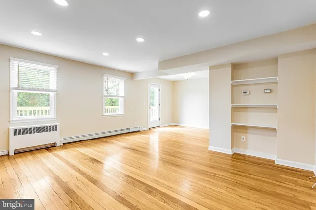 an empty room with wooden floor cabinet and windows