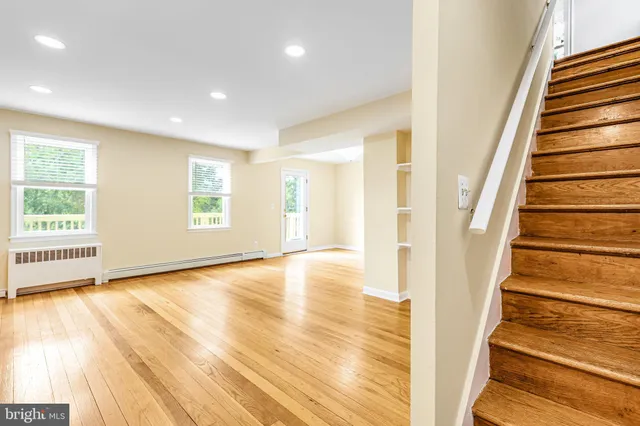 a view of an empty room with wooden floor and stairs