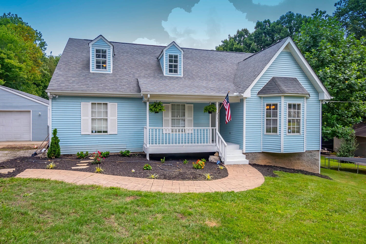a view of a house with a yard plants and large tree